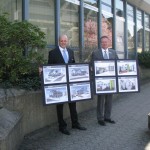 Unser Bild zeigt Ralf Löbach und Andre Schmeis, Vorstand der Bank. Sie zeigen Tafeln mit Bildern des geplanten Umbaus in Much.